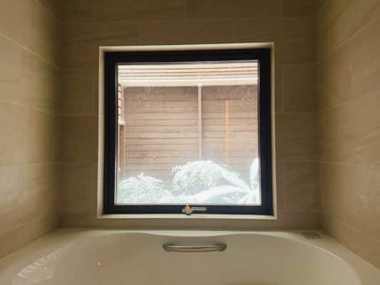 浴室の窓から雪が積もった木が見えている。